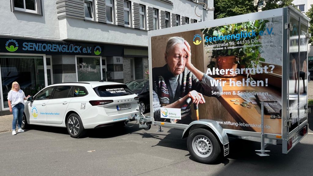 steht vor der Tür unseres Büros in der Kaiserstraße 99, direkt hinter dem neuen Transport-Wagen, einem weißen Skoda. Cornelia Sbosny, unsere 1. Vorsitzende, steht dankbar davor.