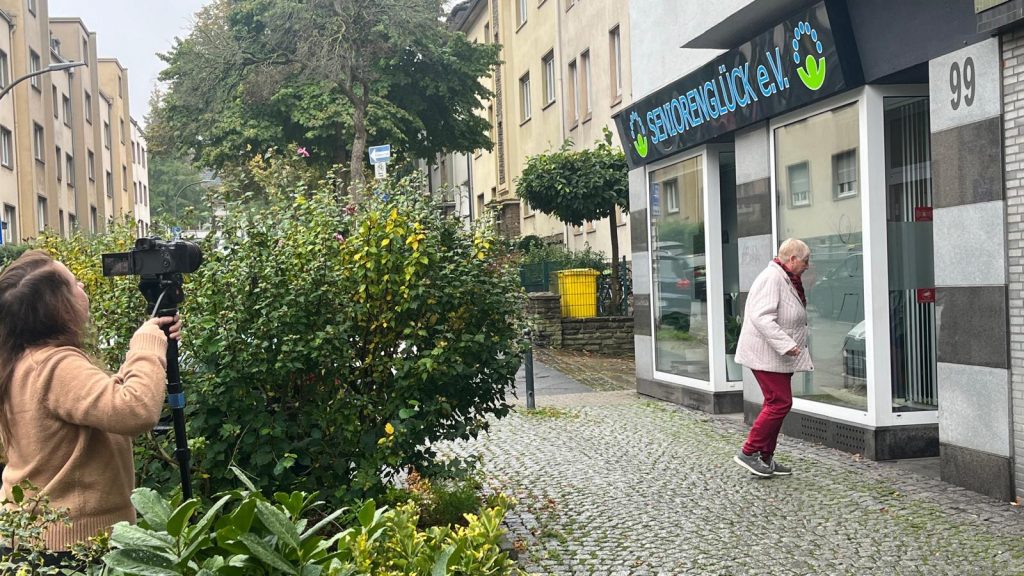 Eingang Seniorenglück e.V., Kaiserstraße 99, 44135 Dortmund: Eine der Seniorinnen kommt an, die Kamerafrau filmt die Szene
