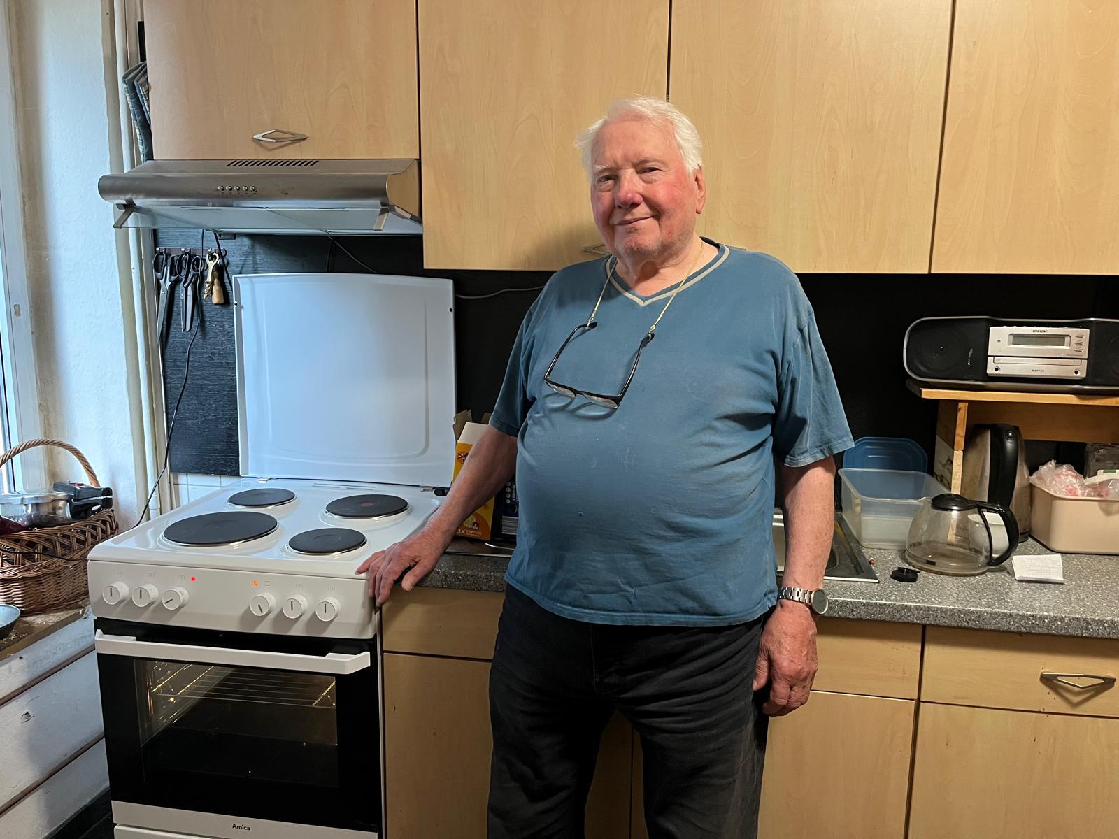 Herr Jäger zeigt seinen neuen Elektro-Herd, den Mitarbeiter von Elektro Weichert direkt in seine Wohnung geliefert haben.