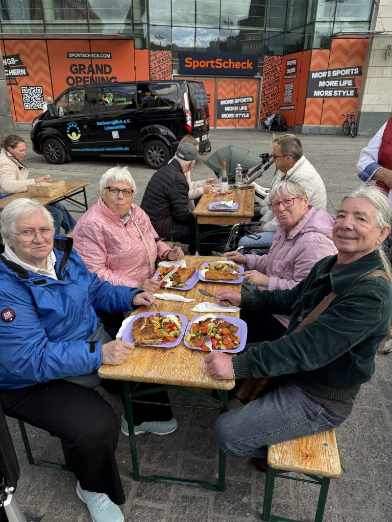 Beim Mittagessen am Marktstand von Tevil's Fischwerk lassen die Seniorinnen und Senioren es sich schmecken