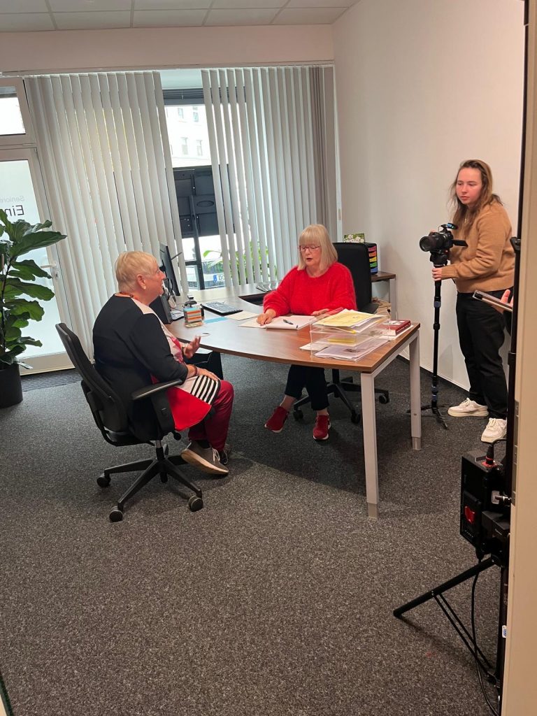 Einzelgespräch zwischen der 1. Vorsitzenden, Cornelia Sbosny und einer Seniorin. Die Kamerafrau filmt die Szene.