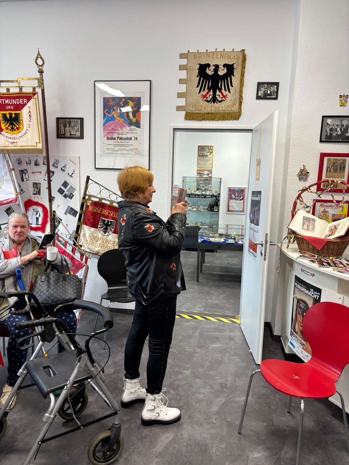 Eine Seniorin macht mit ihrem Handy Fotos von den Karnevals-Schätzen.