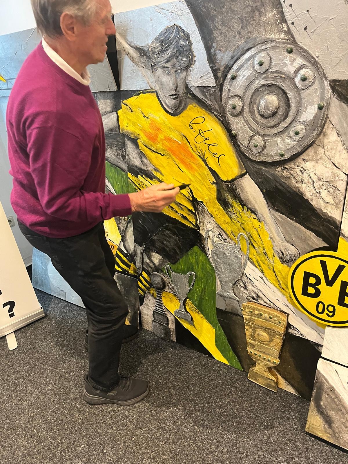 Siggi Held signiert das BVB-Wandbild im Mittelteil des Bildes
