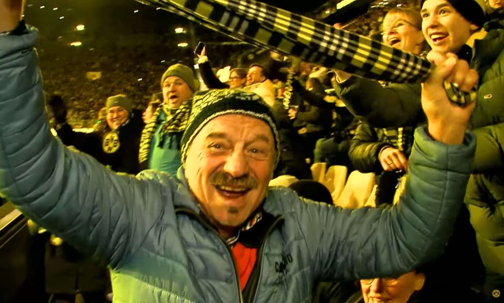 Jubel und Vorfreude im Stadion - ein Zuschauer hält mit vorfreudiger Miene und leuchtenden Augen seinen gelb-schwarz karierten Schal in die Höhe.