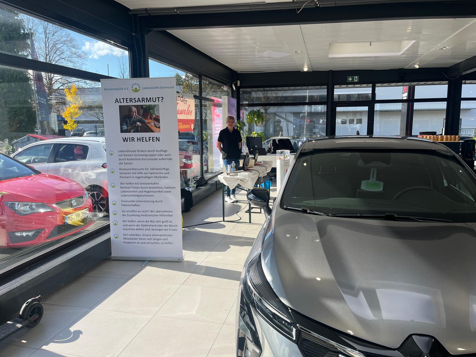 Altersarmut? Wir helfen - steht auf dem großen Aufsteller neben dem Mitsubishi Outlander