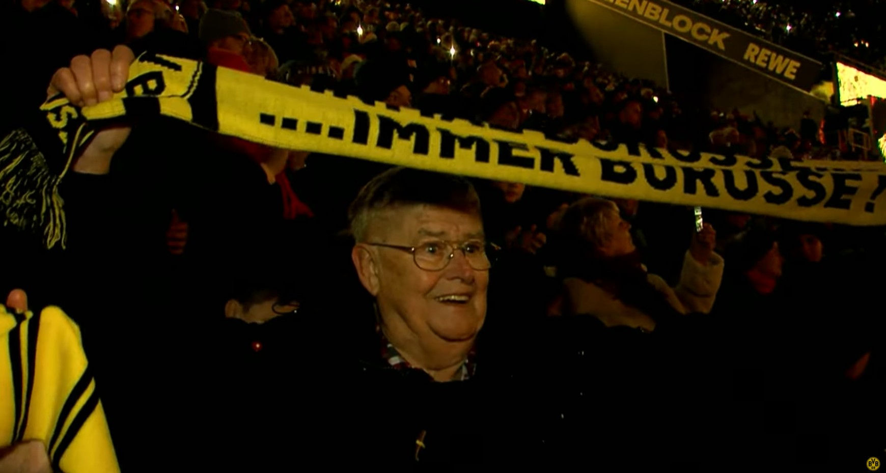 EINMAL BORUSSE... ...IMMER BORUSSE steht in schwarzen Großbuchstaben auf einem hellgelben Schal, den eine Zuschauerin nach oben hält.