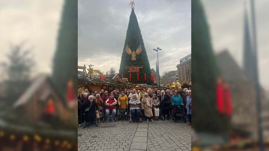 Besuch auf dem Weihnachtsmarkt Dortmund 2025 - Die ganze Seniorengruppe hat sich vor dem großen Christbaum zum Gruppenfoto versammelt