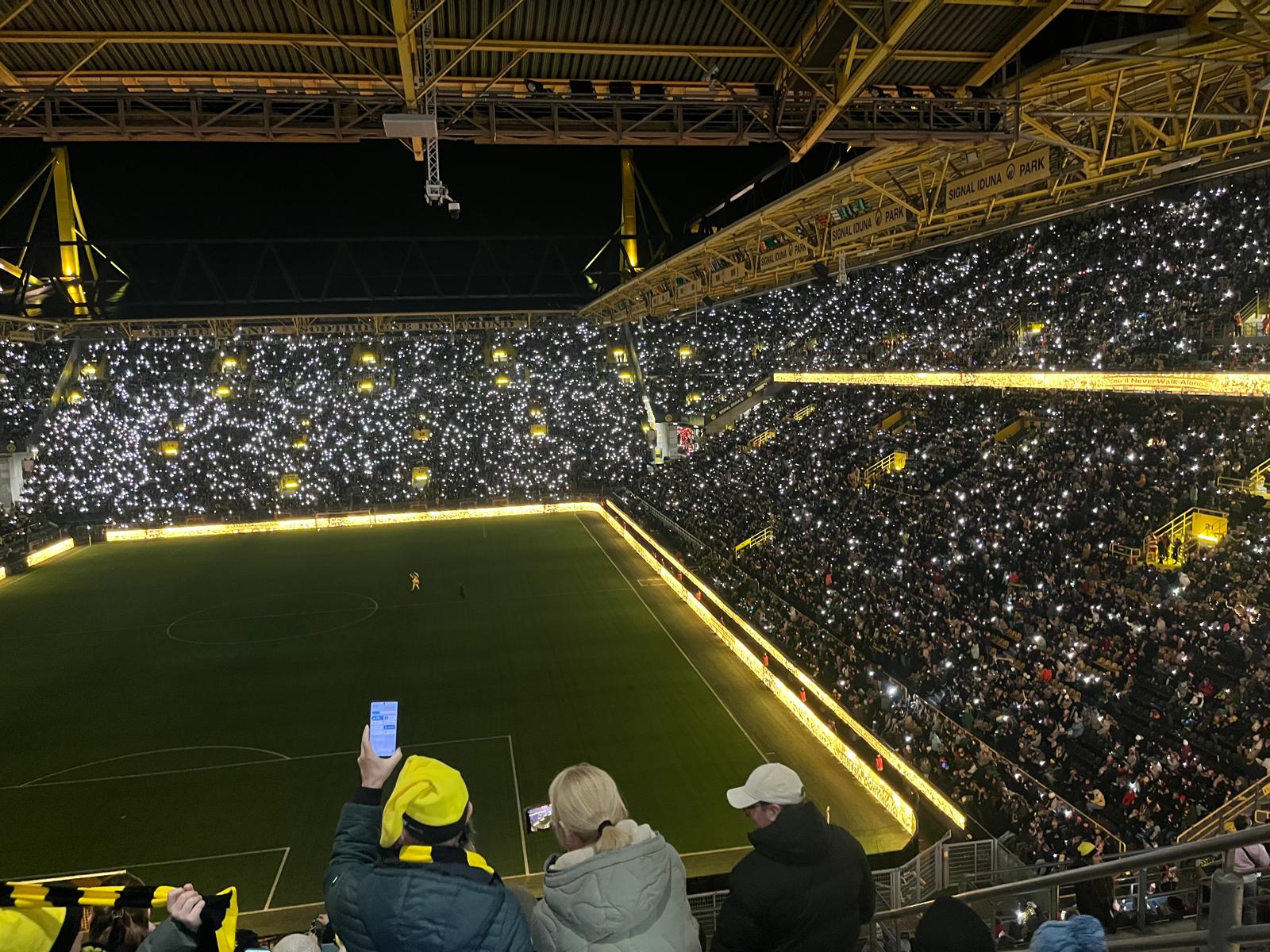 Im hellgelb erleuchteten Stadion machten die Zuschauer von der Tribüne aus erste Fotos mit ihrem Handy.