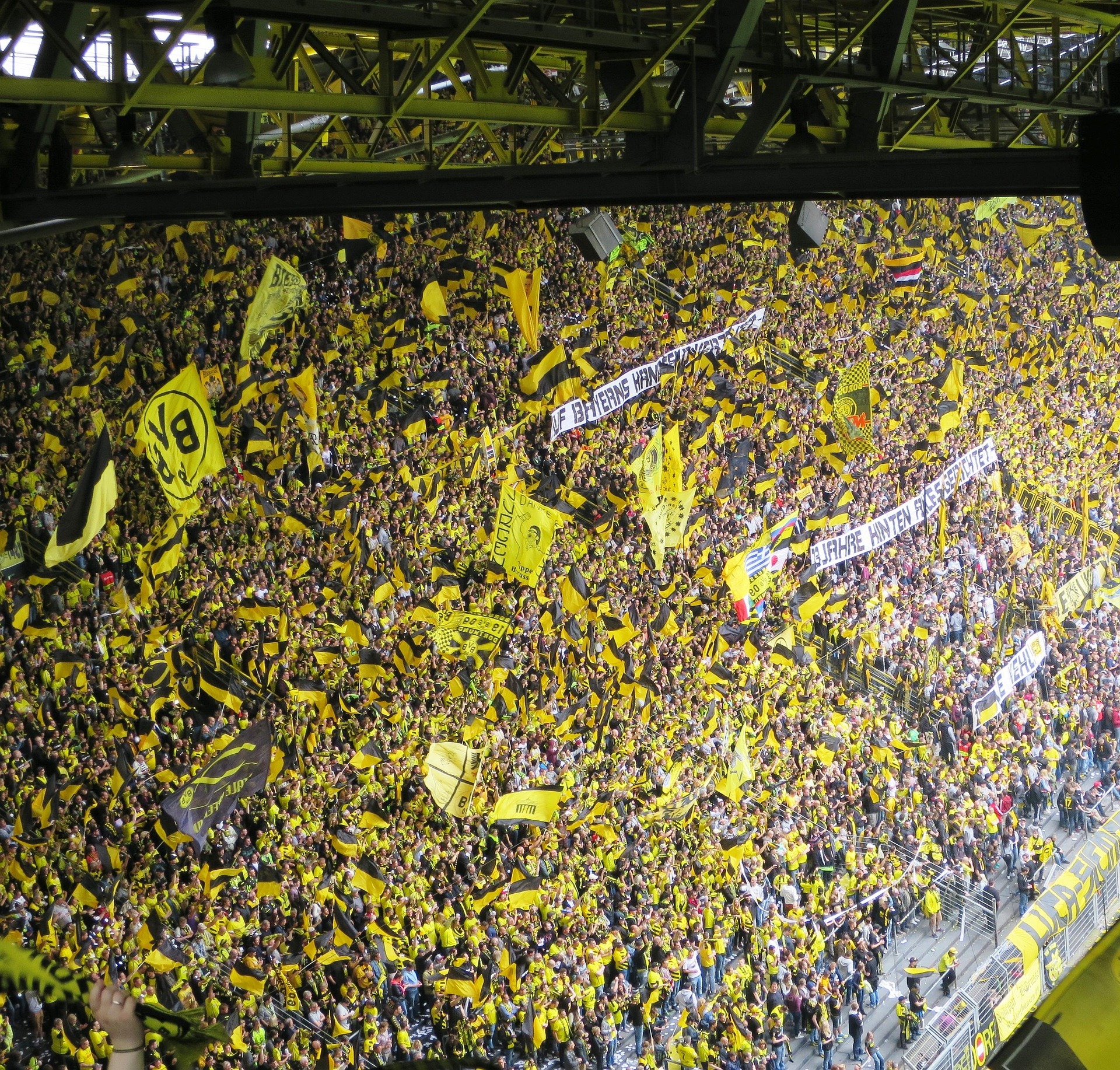 Schwarz-gelber Jubel im BVB-Stadion - Die Fans und Zuschauer jubeln den Spielern zu und schwingen die schwarz-gelben BVB-Flaggen. Die meisten tragen gelb-schwarze BVB-T-Shirts.