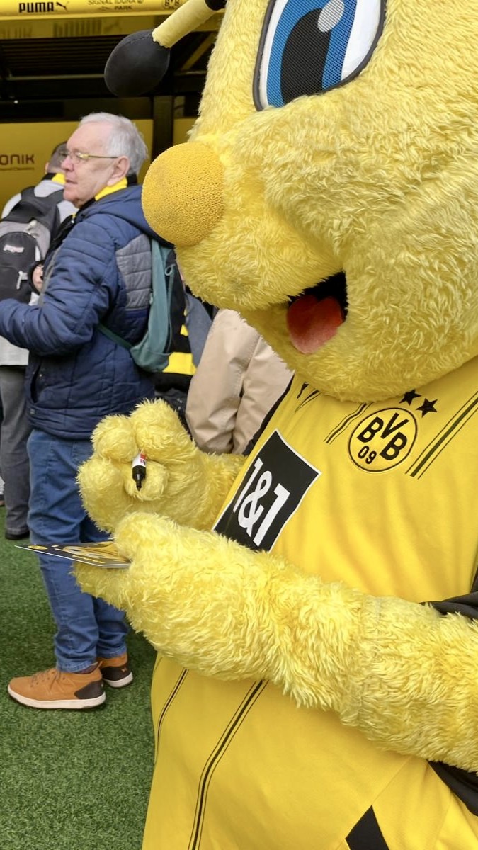 Das BVB-Maskottchen schreibt schon fleißig Autogramme.