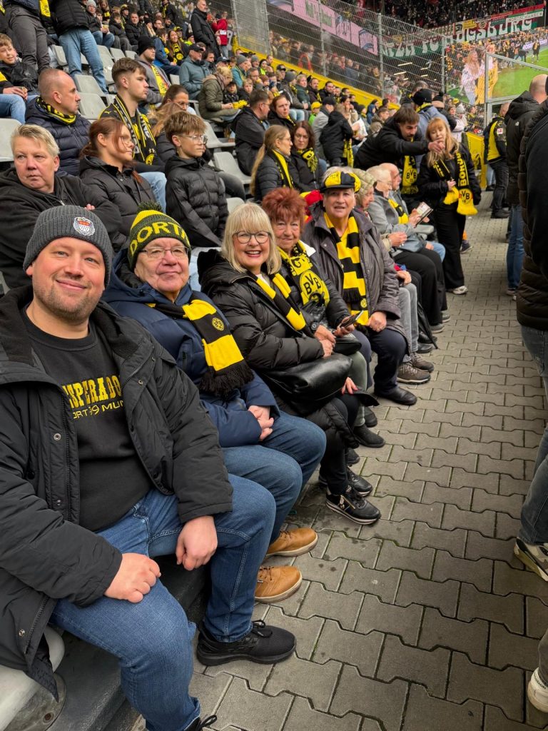 Mit Mützen und Schals in den BVB-Farben Schwarz und Gelb sitzen die Senioren im Stadion.