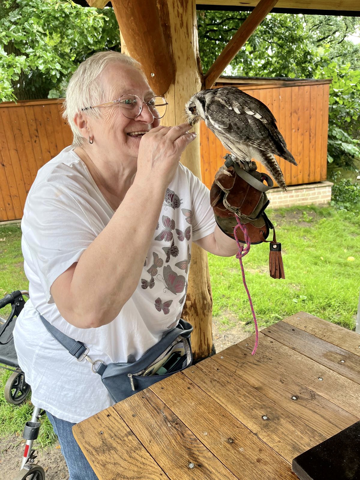 Eine Seniorin streichelt eine zahme Eule beim Ausflug zum Hof Sebbel am Halterner See.