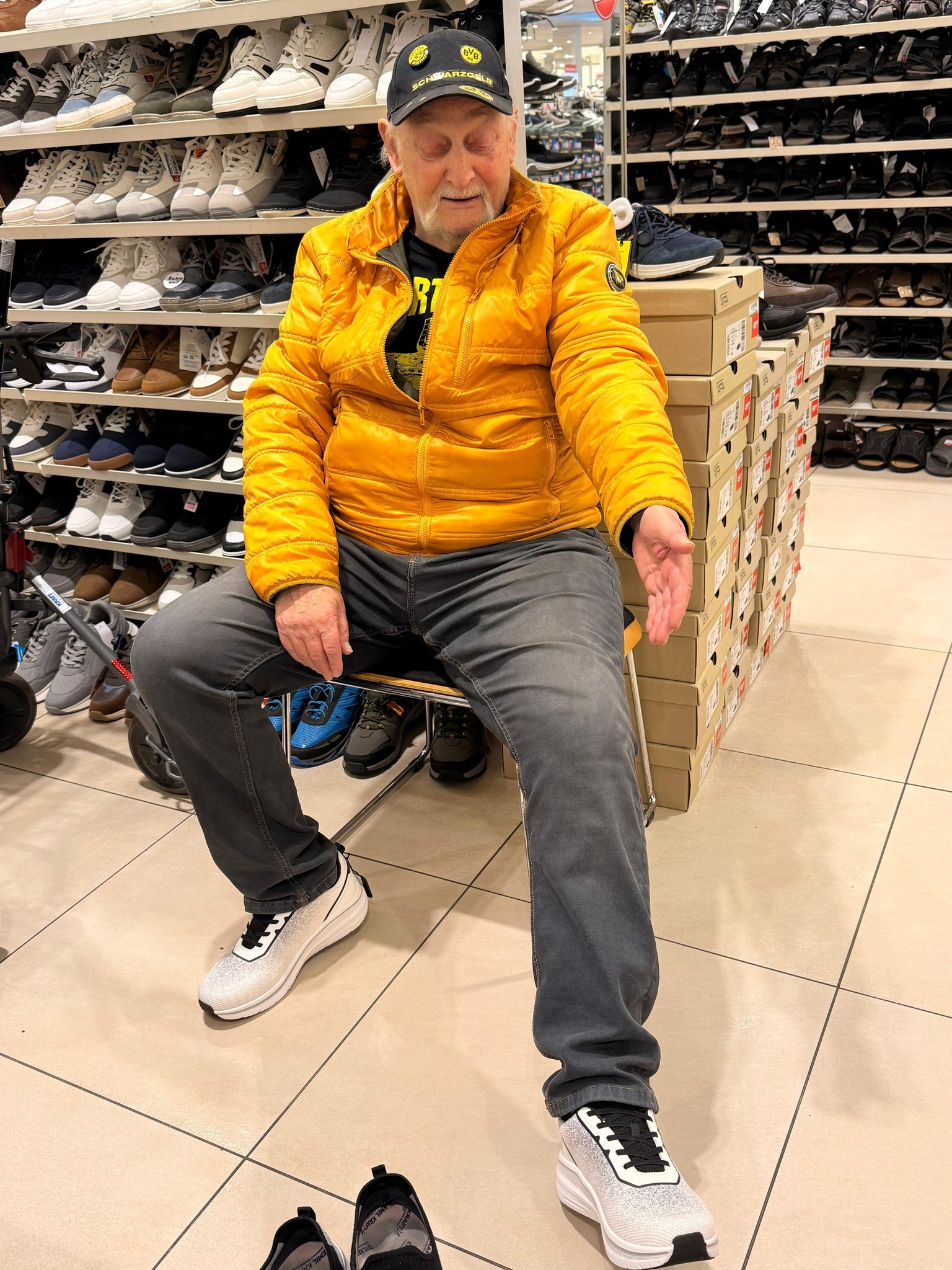 Der Senior probiert ein Paar grau-weiße Turnschuhe mit schwarzer Schnürung an.