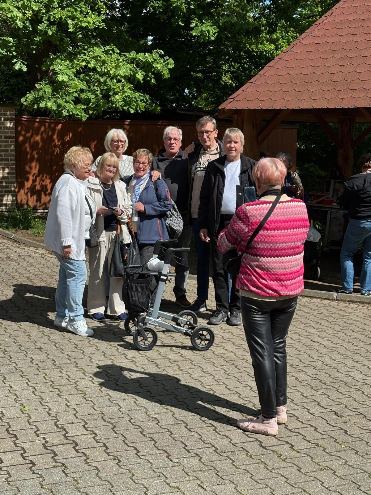 Eine Seniorin macht von den anderen ein Gruppenfoto.