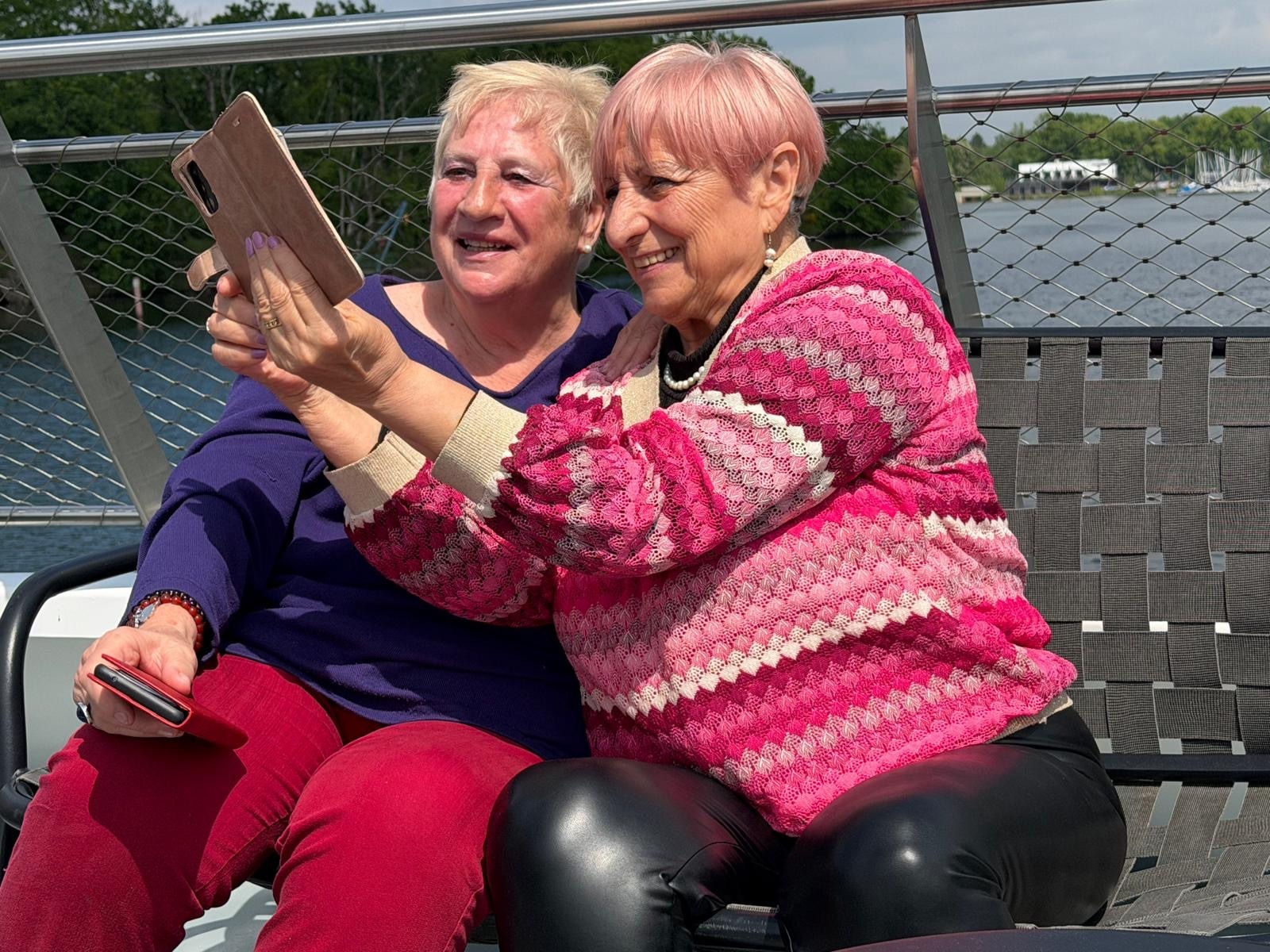 Zwei der Seniorinnen schießen mit ihrer Handy-Kamera einen gemeinsamen Selfie.