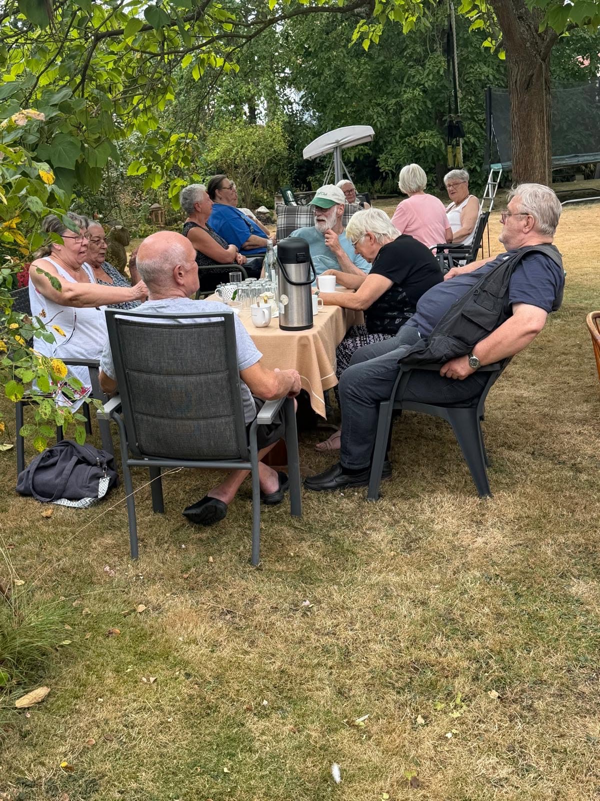 Die Gäste sitzen am Gartentisch und trinken frischen heißen Kaffee.