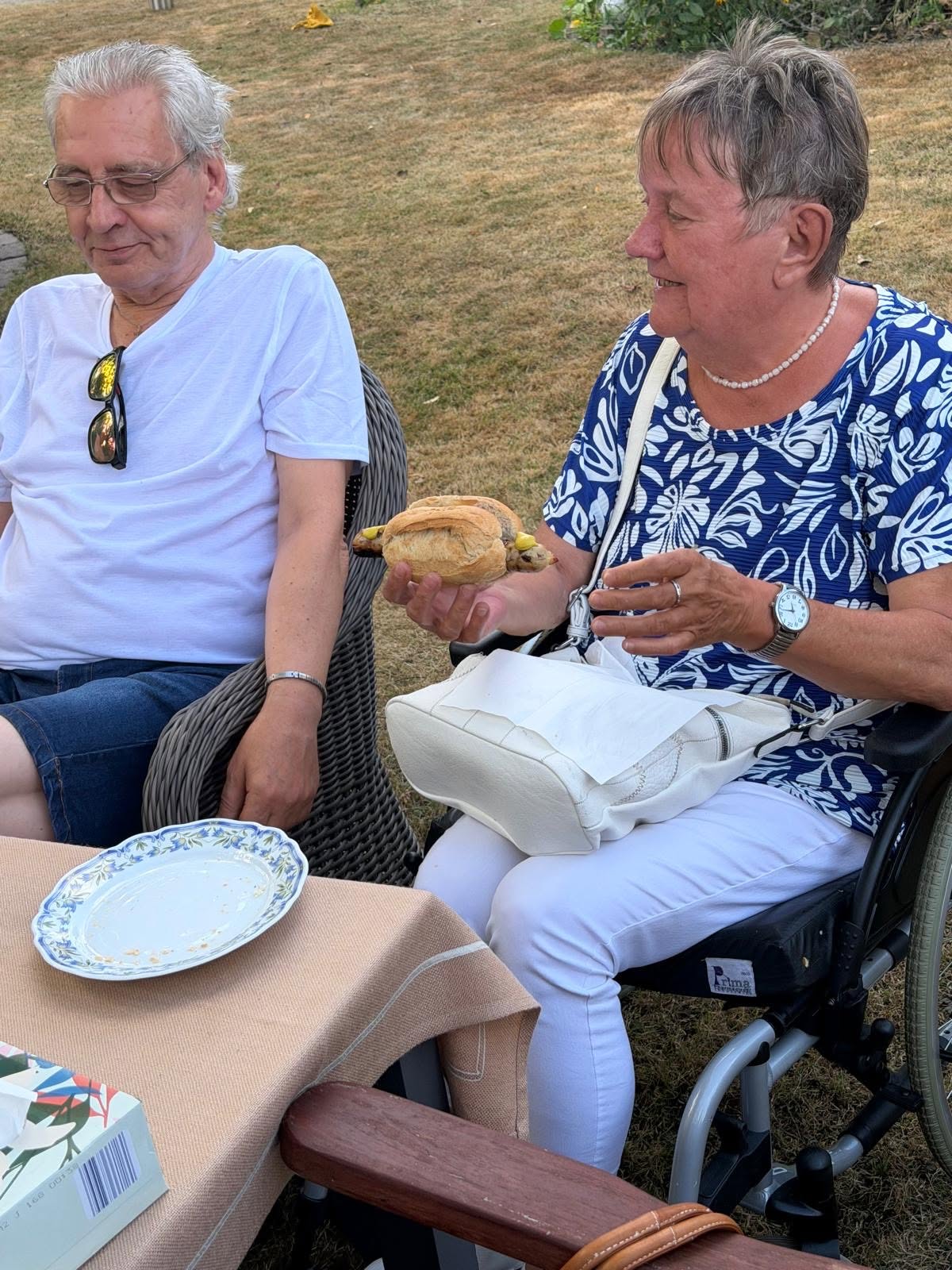 Eine Seniorin lässt sich Bratwurst mit Brötchen und Senf schmecken.