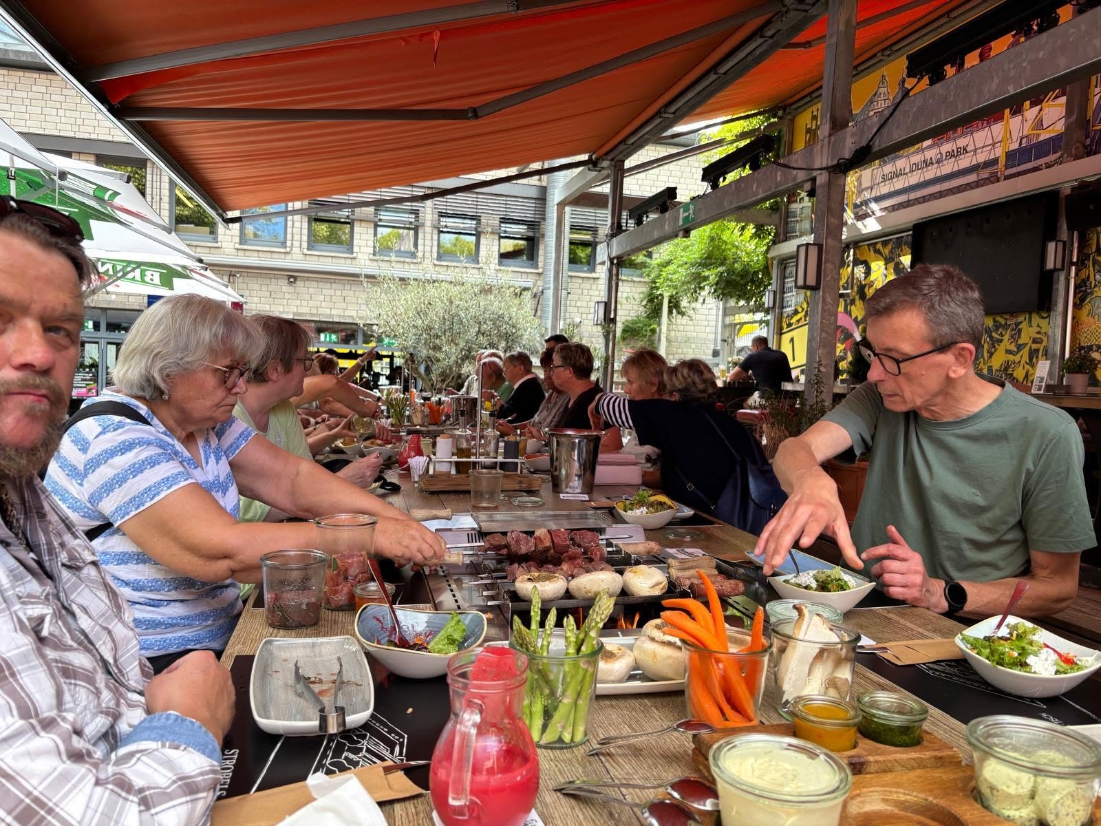 Eine Seniorin legt Spieße mit Rind- und Schweinefleisch auf den Grill.